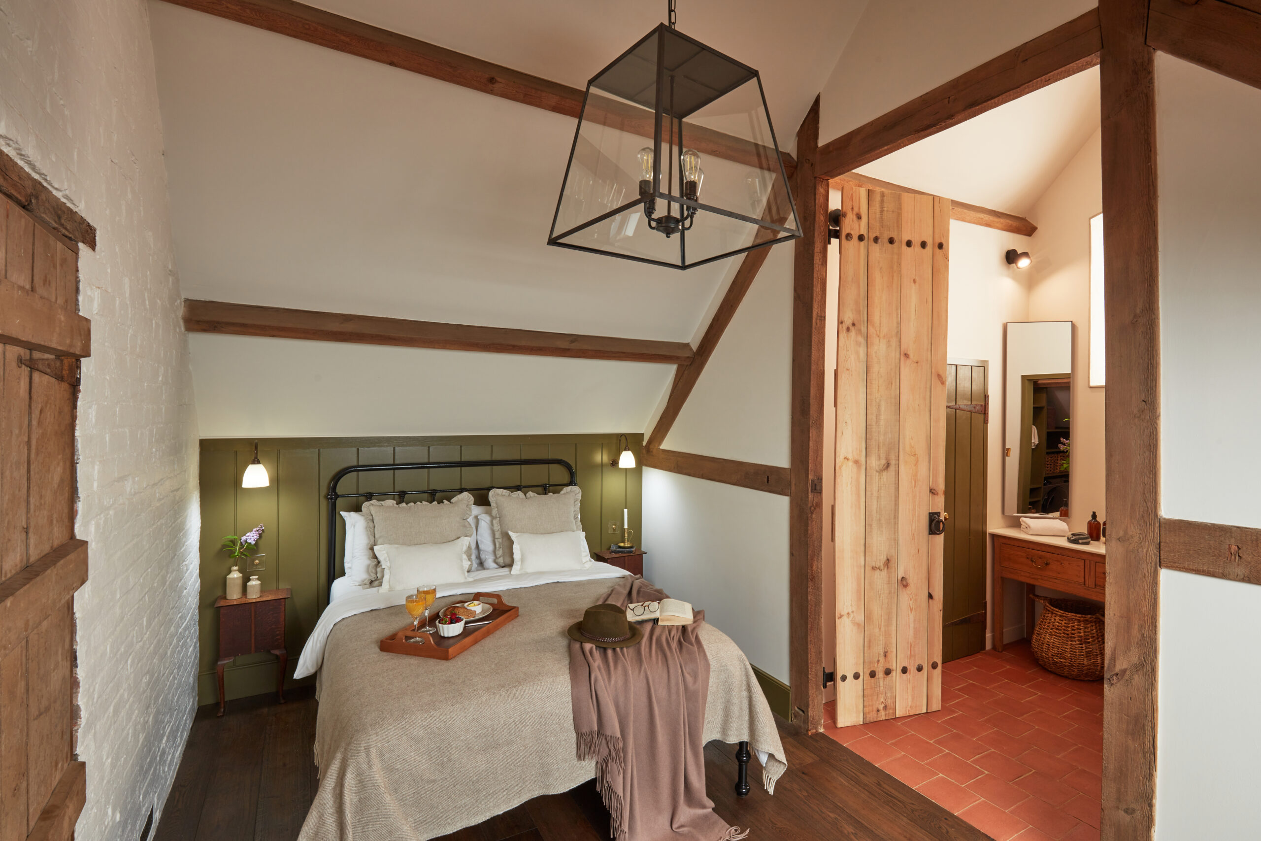 As seen on Saving the Manor, the restored hay loft bedroom and bathroom with utility room, dividing doors, oak flooring with underfloor heating, wood paneling and vaulted ceiling.